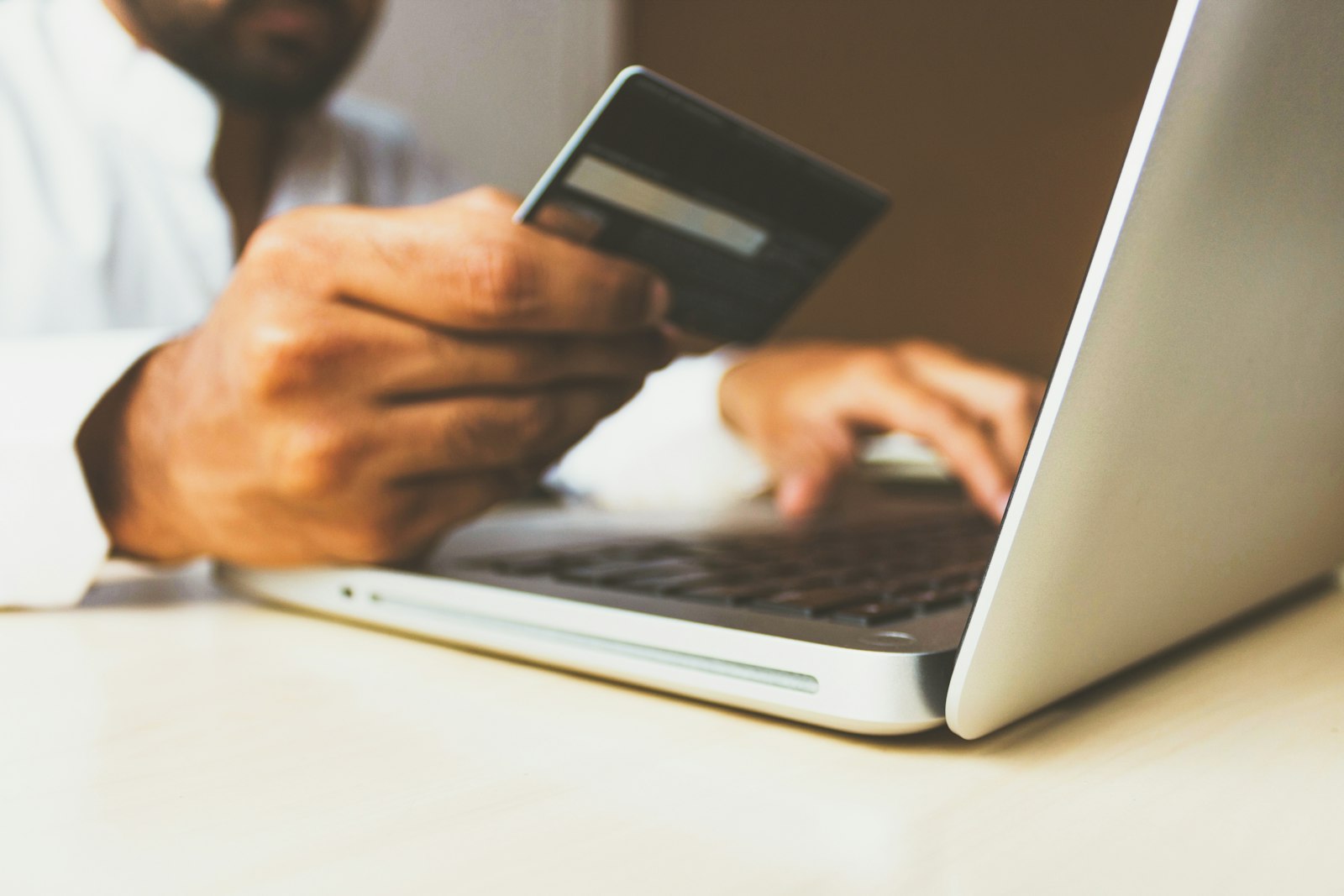 Pessoa comparando produtos no notebook com o cartão na mão, representando o comércio agêntico em que a IA pesquisa a compra e o site fecha a venda