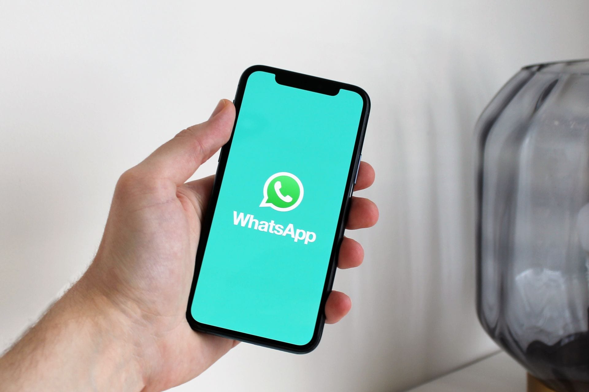Mão segurando celular com conversa aberta, o WhatsApp na geração de leads com IA