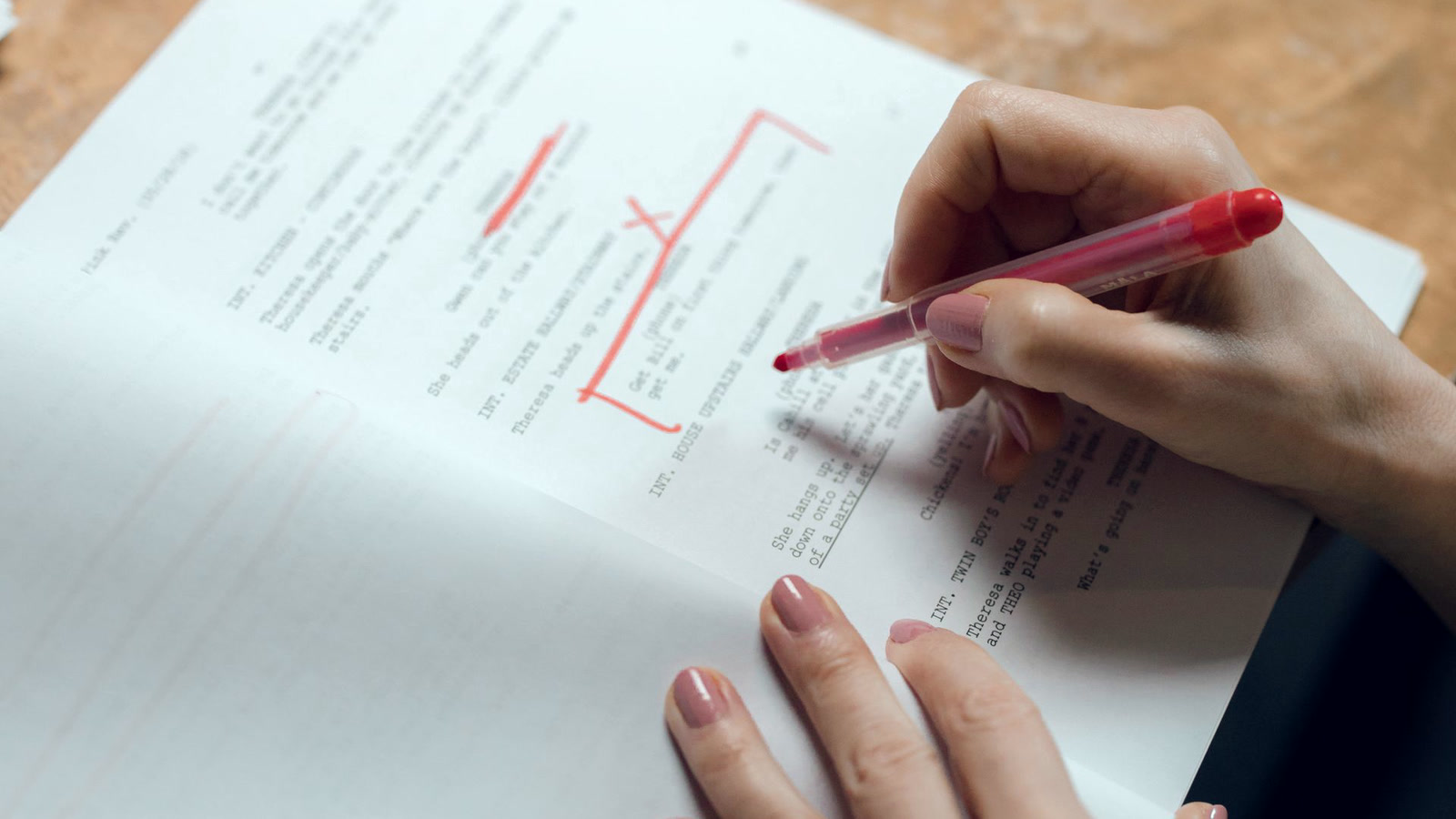 Mão revisando texto impresso com caneta vermelha, a revisão humana que protege a voz da marca
