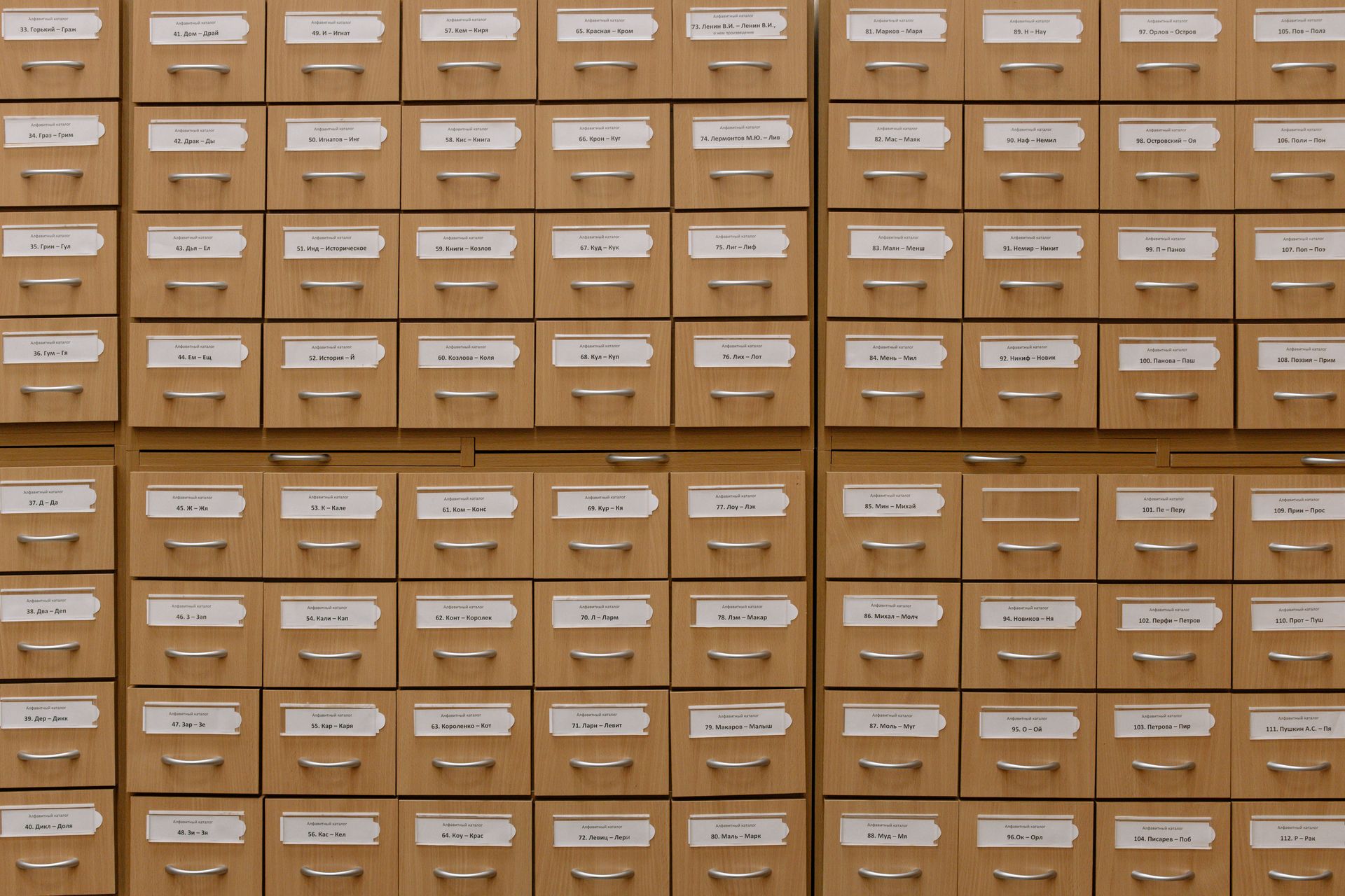 Parede de gavetas de catálogo de biblioteca com etiquetas de índice, metáfora da recuperação sob demanda na engenharia de contexto