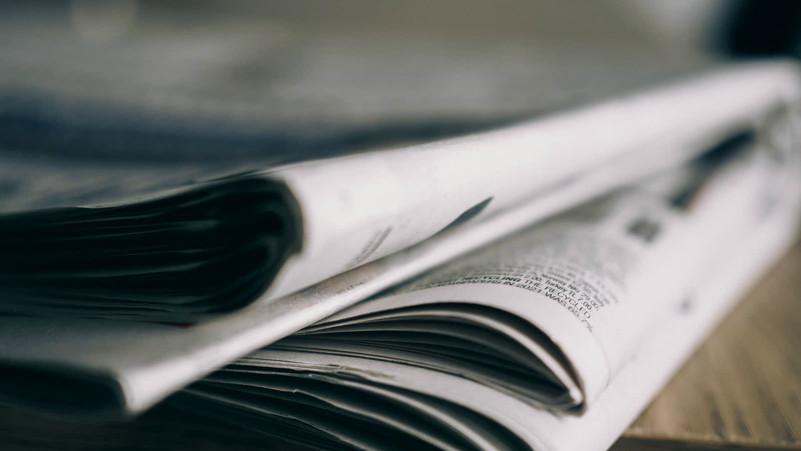Jornal impresso dobrado sobre mesa de madeira, metáfora da Time vendendo Agent Ads