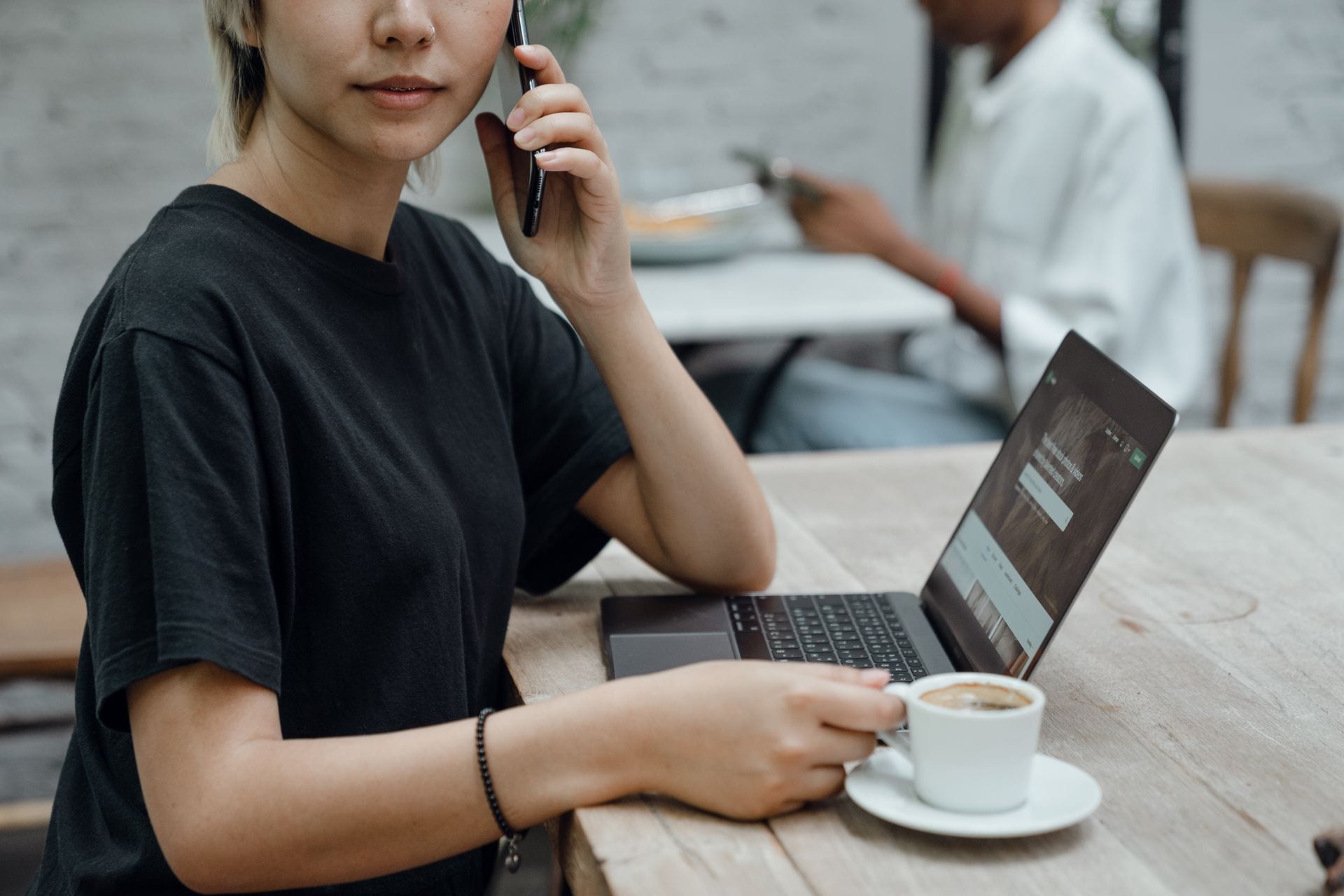 Profissional trabalhando de notebook num café, o novo desenho de equipe que o orçamento de IA na agência de marketing puxa
