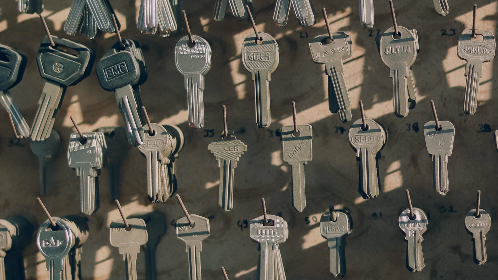 Parede com dezenas de chaves penduradas e numeradas, imagem dos acessos que o onboarding de agentes de IA precisa registrar