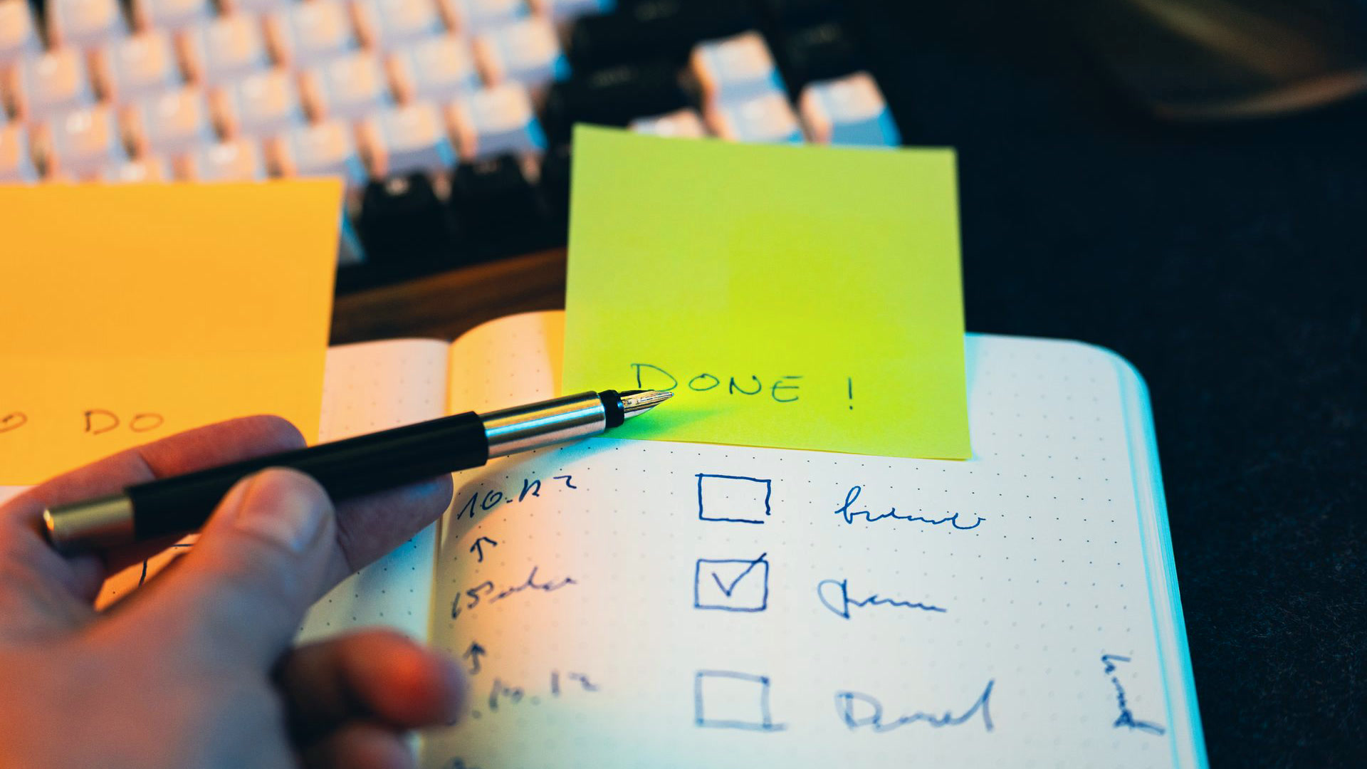 Caderno com checklist e post-it escrito done ao lado do teclado, a rotina de revisão do planejamento de marketing da operação